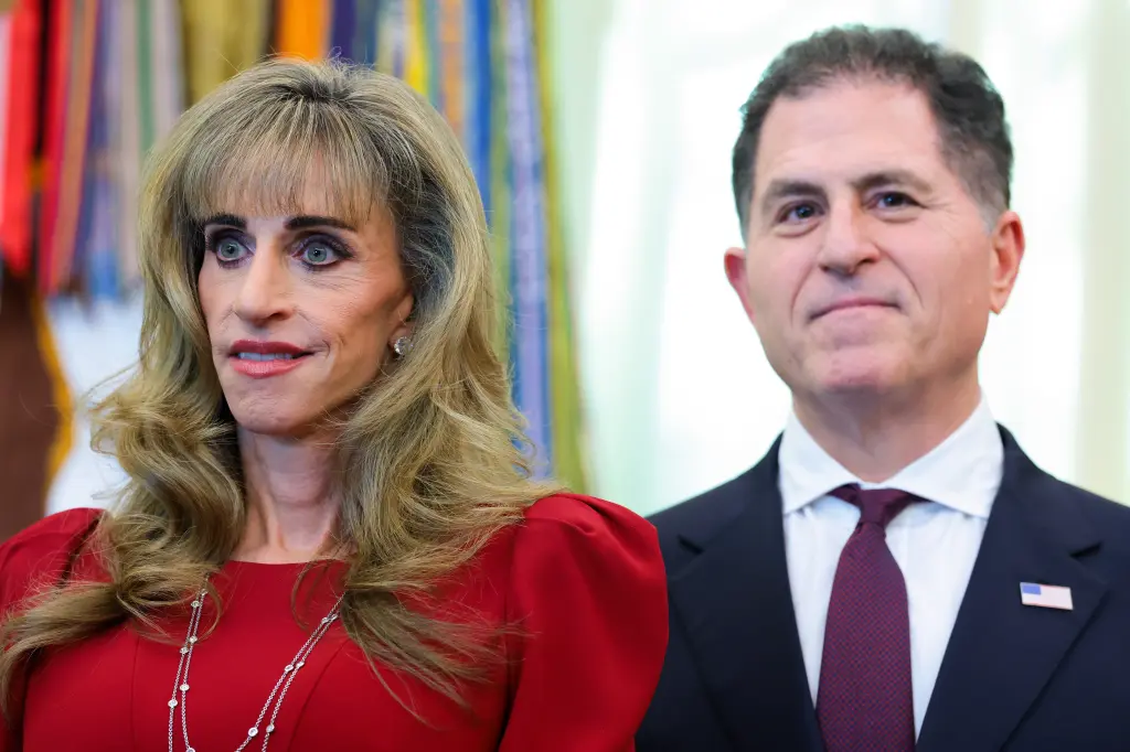 Susan Dell in a red dress stands beside Michael Dell in a dark suit at a formal event